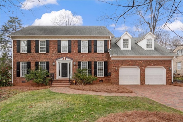 colonial inspired home with crawl space, a garage, decorative driveway, and brick siding