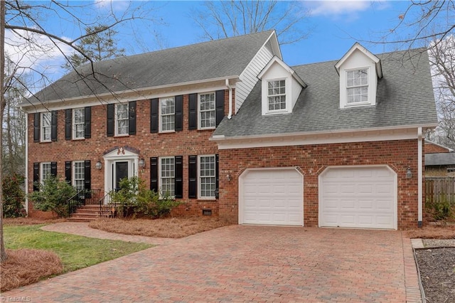 colonial house featuring brick siding, a shingled roof, and decorative driveway