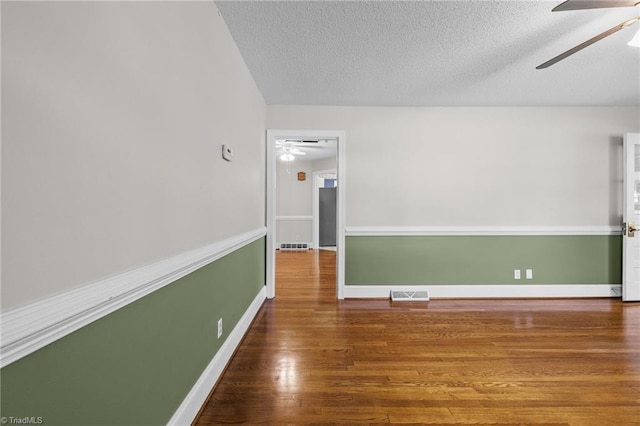 empty room with a textured ceiling, hardwood / wood-style flooring, and ceiling fan