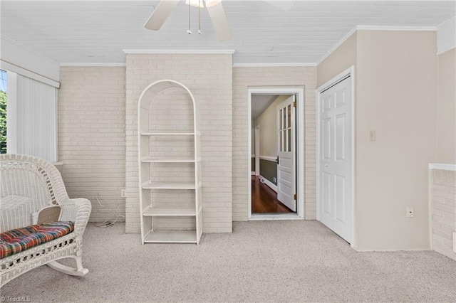 sitting room with light colored carpet, ceiling fan, ornamental molding, and brick wall