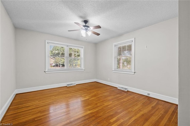 empty room featuring ceiling fan, wood-type flooring, and a textured ceiling