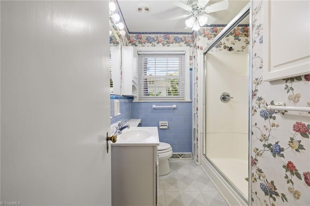 bathroom with ceiling fan, a shower with door, vanity, and toilet