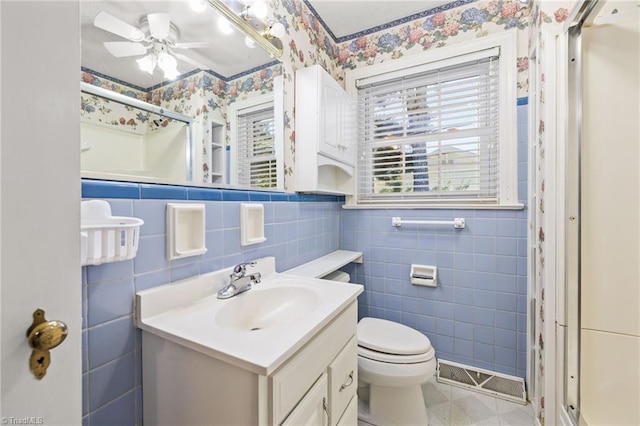 bathroom featuring walk in shower, vanity, ceiling fan, tile walls, and toilet