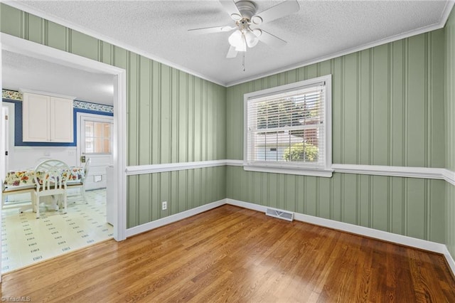 unfurnished room featuring hardwood / wood-style floors, a textured ceiling, ceiling fan, and ornamental molding