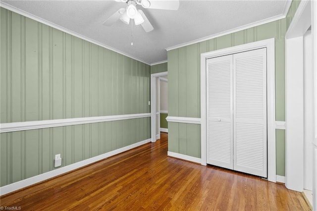 unfurnished bedroom featuring ornamental molding, a textured ceiling, ceiling fan, hardwood / wood-style flooring, and a closet