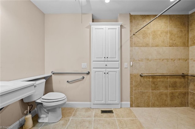 bathroom with tile patterned flooring, toilet, and a tile shower