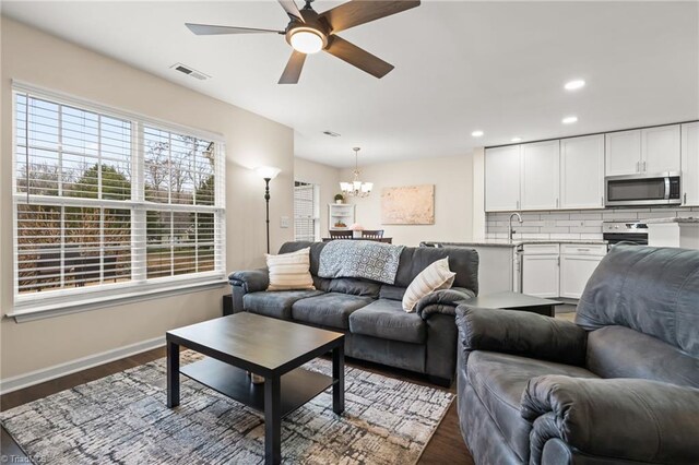 living room featuring sink, ceiling fan with notable chandelier, and dark hardwood / wood-style floors