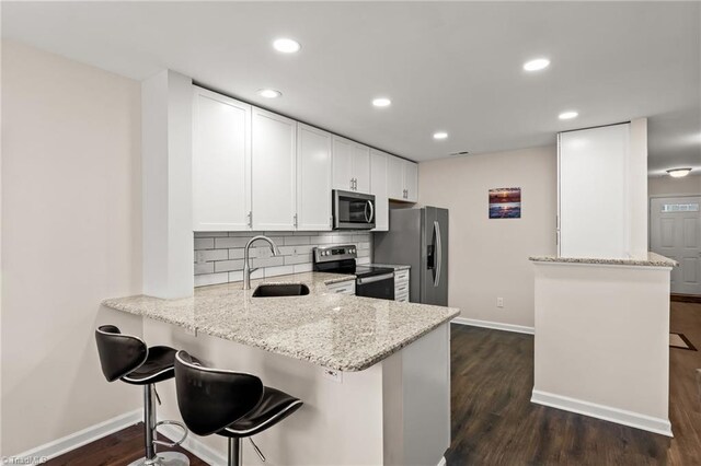 kitchen featuring sink, kitchen peninsula, a breakfast bar area, and appliances with stainless steel finishes