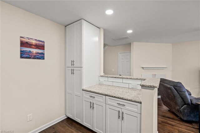 kitchen with kitchen peninsula, dark hardwood / wood-style floors, white cabinetry, and light stone countertops