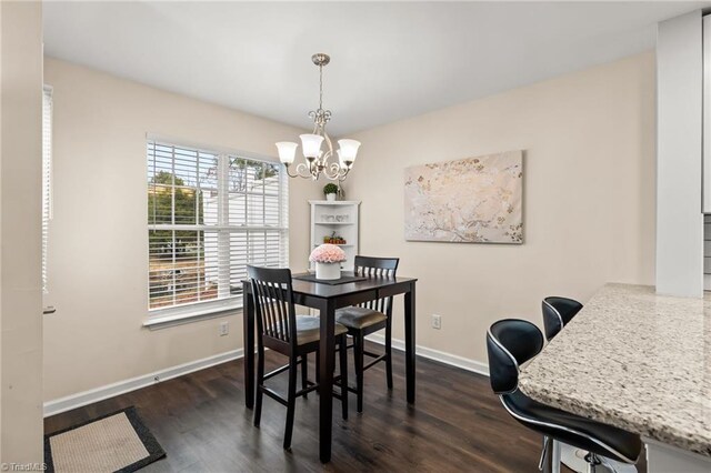 dining space with dark wood-type flooring and an inviting chandelier