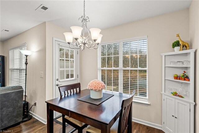 dining area featuring a healthy amount of sunlight, dark hardwood / wood-style floors, and a notable chandelier