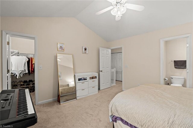 carpeted bedroom featuring a walk in closet, vaulted ceiling, ceiling fan, connected bathroom, and a closet