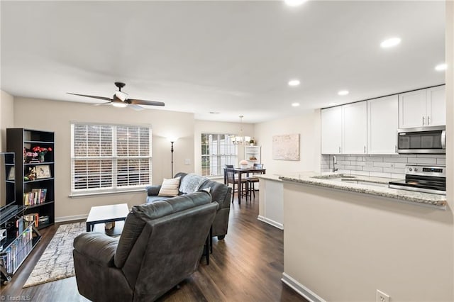 living room with ceiling fan with notable chandelier and dark hardwood / wood-style floors