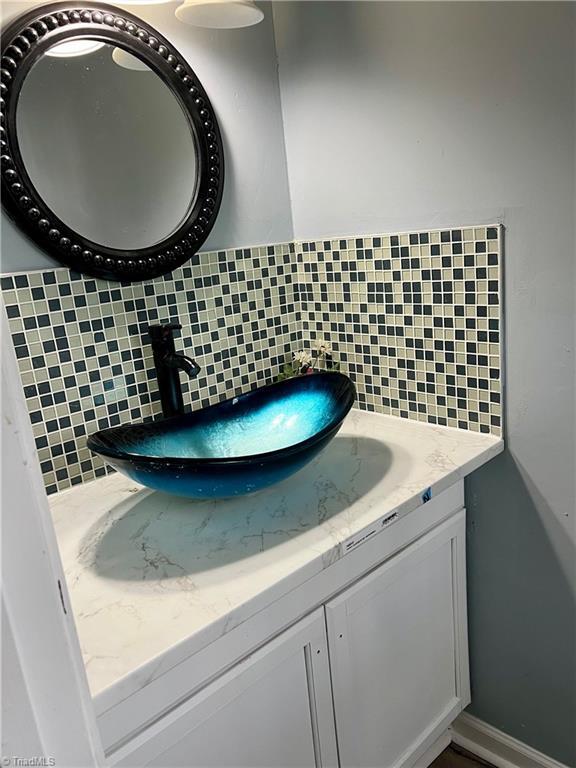 bathroom featuring baseboards, backsplash, and vanity