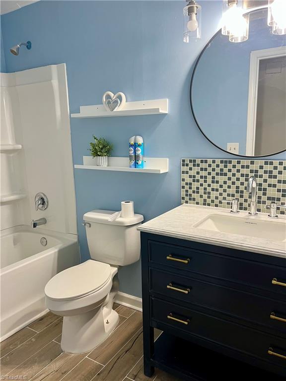 full bathroom with vanity, shower / bath combination, tasteful backsplash, and wood finish floors