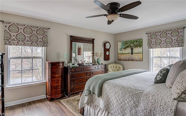 bedroom featuring ceiling fan, wood-type flooring, and multiple windows