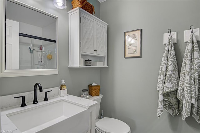 bathroom featuring vanity, a shower with shower door, and toilet