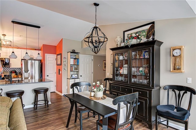 dining space with dark hardwood / wood-style flooring, sink, and a chandelier