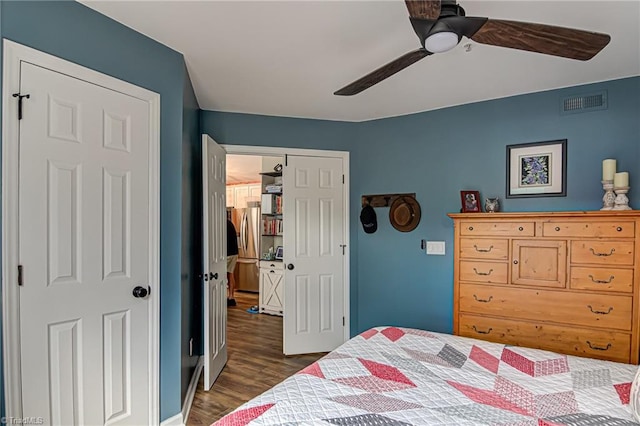 bedroom featuring ceiling fan, dark wood-type flooring, stainless steel refrigerator with ice dispenser, and a closet