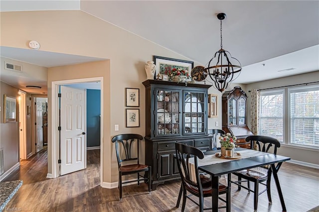 dining area featuring dark hardwood / wood-style flooring, vaulted ceiling, and a notable chandelier