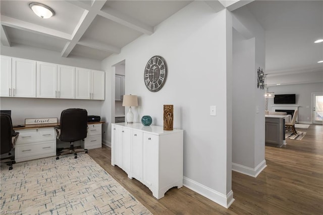 office area featuring beamed ceiling, coffered ceiling, hardwood / wood-style flooring, and built in desk