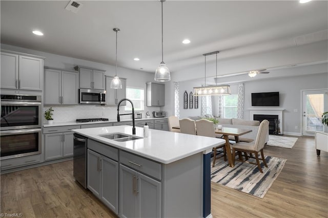 kitchen with gray cabinetry, stainless steel appliances, a sink, visible vents, and light countertops