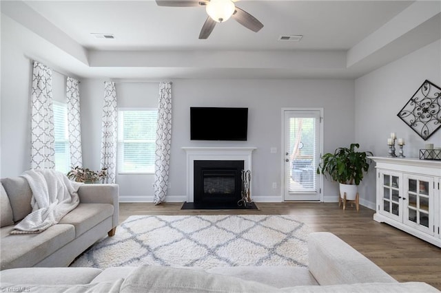 living room featuring a tray ceiling, ceiling fan, and wood-type flooring