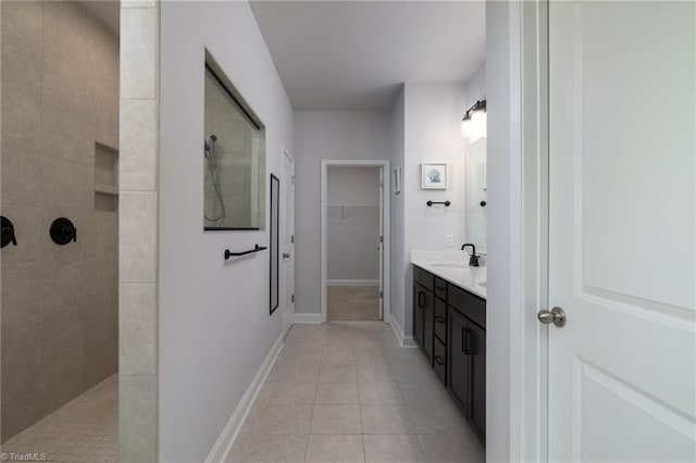 bathroom with baseboards, tile patterned floors, a spacious closet, walk in shower, and vanity