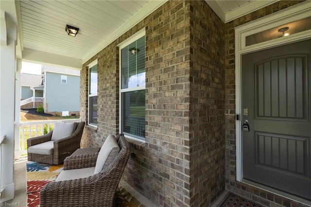 entrance to property featuring a porch and brick siding