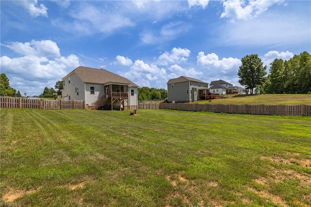 view of yard featuring a sunroom, a fenced backyard, and stairs