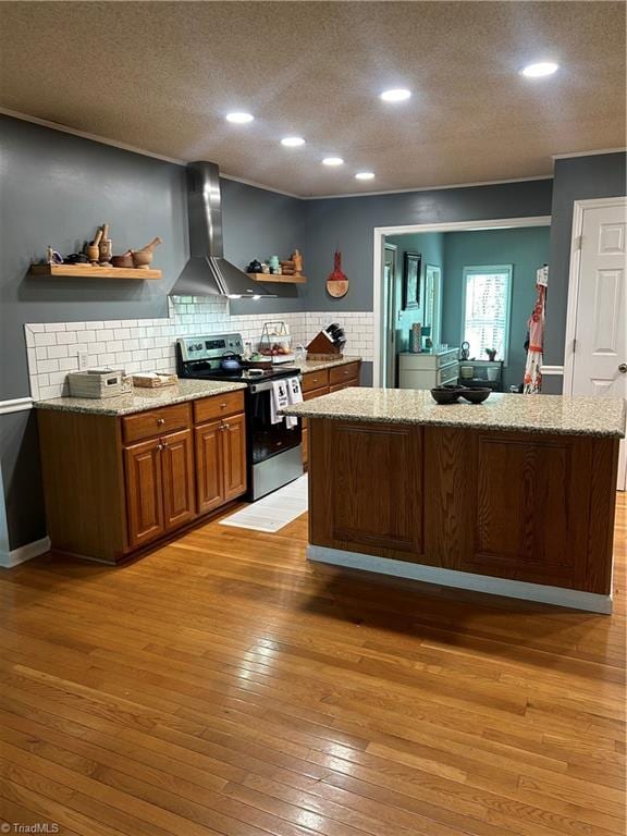 kitchen with stainless steel range with electric stovetop, a textured ceiling, light wood-type flooring, and wall chimney range hood