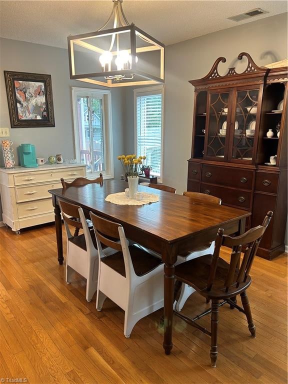 dining area featuring light hardwood / wood-style floors, an inviting chandelier, and a textured ceiling