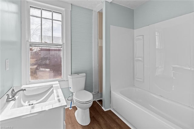 bathroom with a tub to relax in, a healthy amount of sunlight, toilet, and wood finished floors