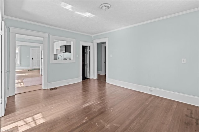 empty room with crown molding, visible vents, and wood finished floors