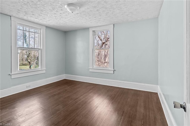 spare room featuring a textured ceiling, baseboards, and dark wood-style flooring