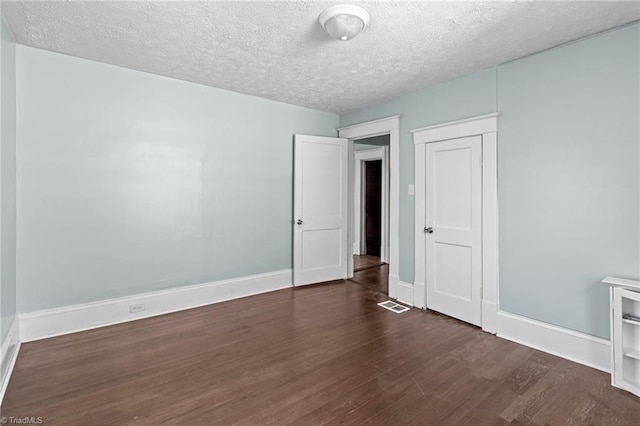 unfurnished bedroom featuring baseboards, dark wood finished floors, and a textured ceiling