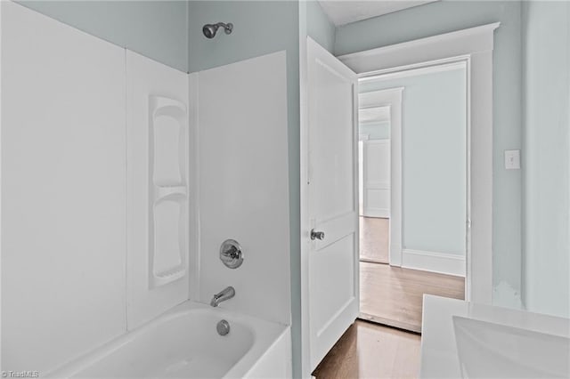 bathroom with washtub / shower combination and wood finished floors