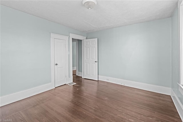 spare room featuring a textured ceiling, wood finished floors, and baseboards