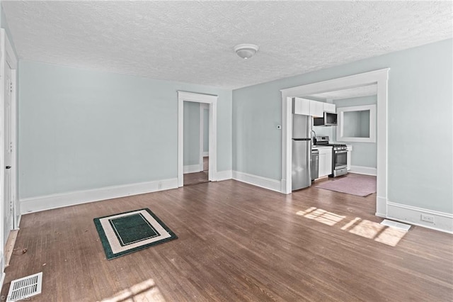 unfurnished living room with baseboards, a textured ceiling, visible vents, and dark wood-style flooring