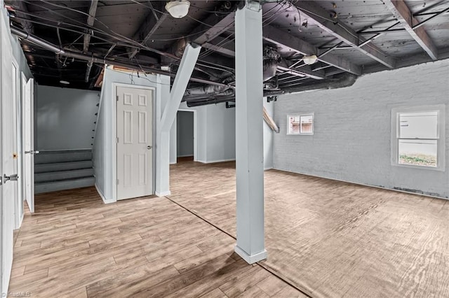 basement with stairs, brick wall, and wood finished floors