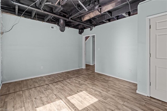 below grade area featuring wood finished floors, visible vents, and baseboards