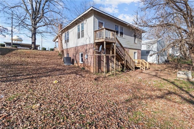 back of property with a chimney, brick siding, stairway, and central AC unit