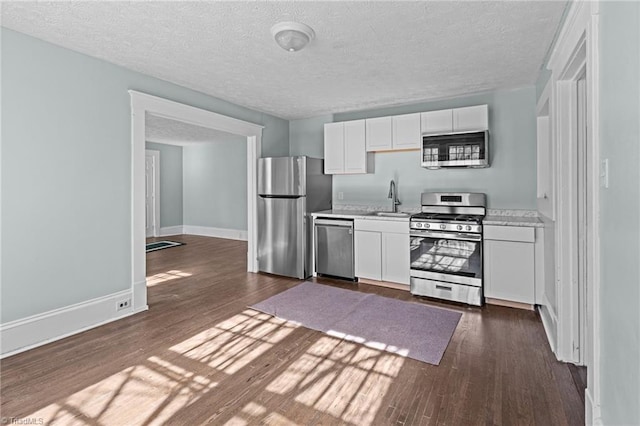 kitchen featuring a sink, white cabinetry, light countertops, appliances with stainless steel finishes, and dark wood-style floors