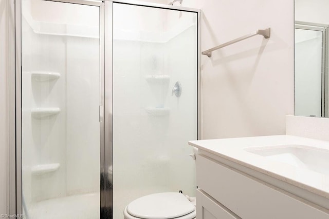 bathroom featuring vanity, an enclosed shower, and toilet