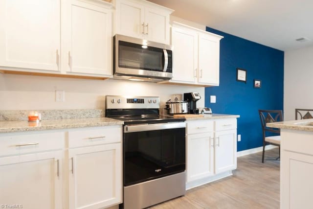 kitchen with white cabinetry, light stone counters, light hardwood / wood-style flooring, and stainless steel appliances