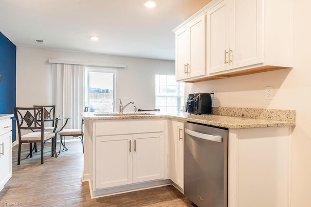 kitchen featuring hardwood / wood-style floors, white cabinetry, sink, stainless steel dishwasher, and light stone countertops