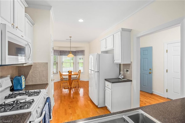 kitchen featuring dark countertops, light wood finished floors, decorative backsplash, and white appliances