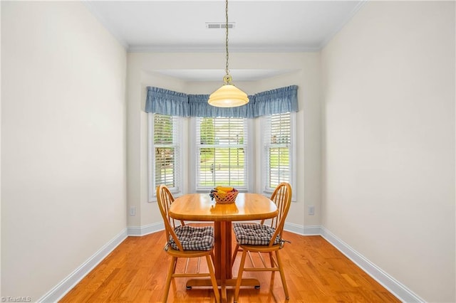 dining space with visible vents, ornamental molding, light wood-style flooring, and baseboards