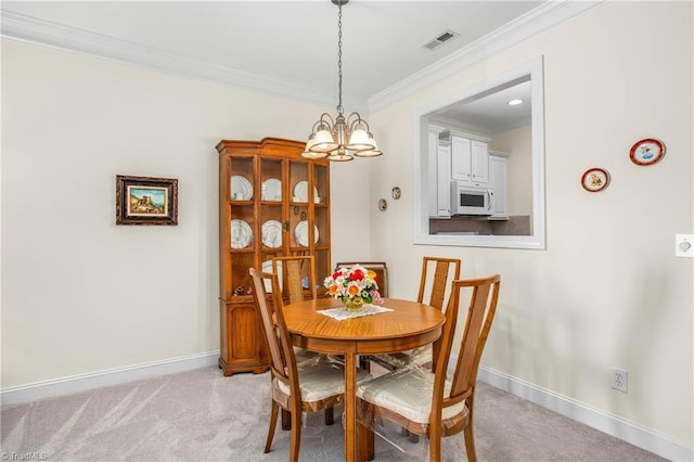dining room with visible vents, crown molding, a chandelier, and light colored carpet