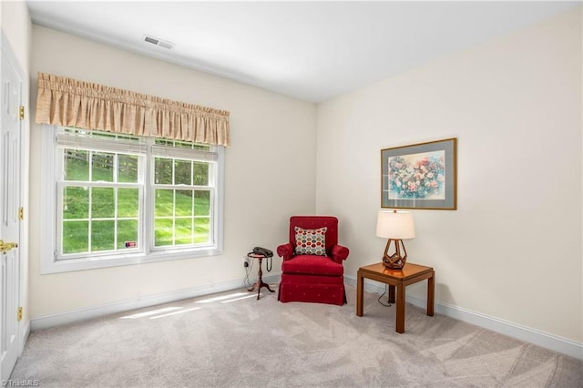 living area with baseboards, visible vents, and carpet